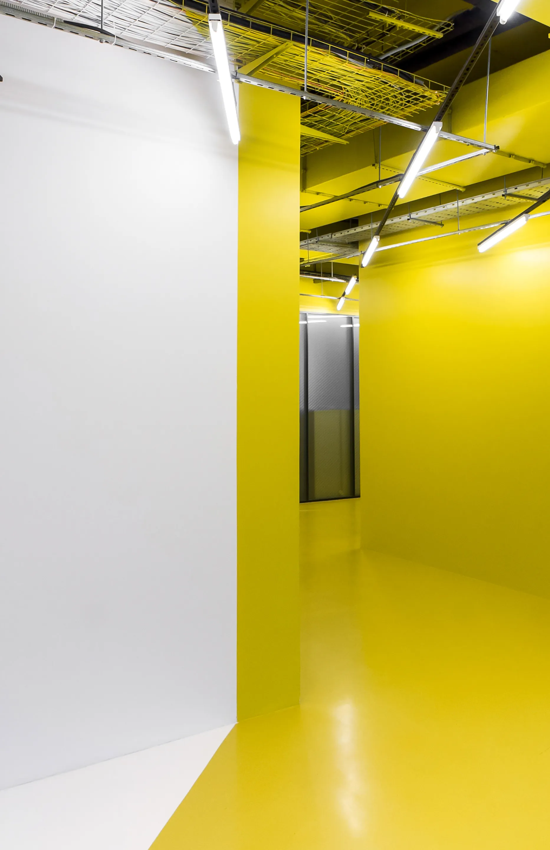A yellow corridor beyond the white wall